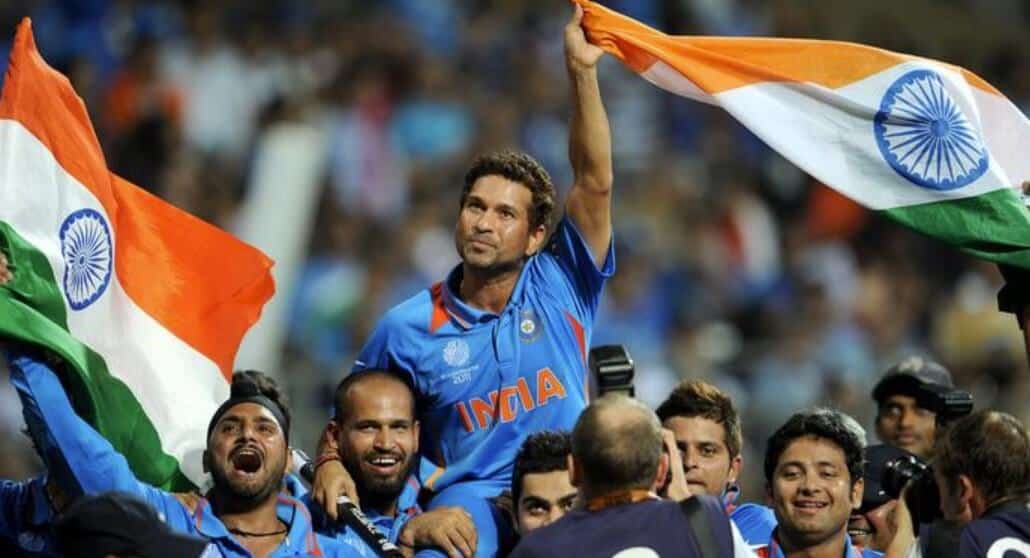 Sachin Tendulkar, one of the top Indian cricket players of all time, celebrates while holding up the Indian flag